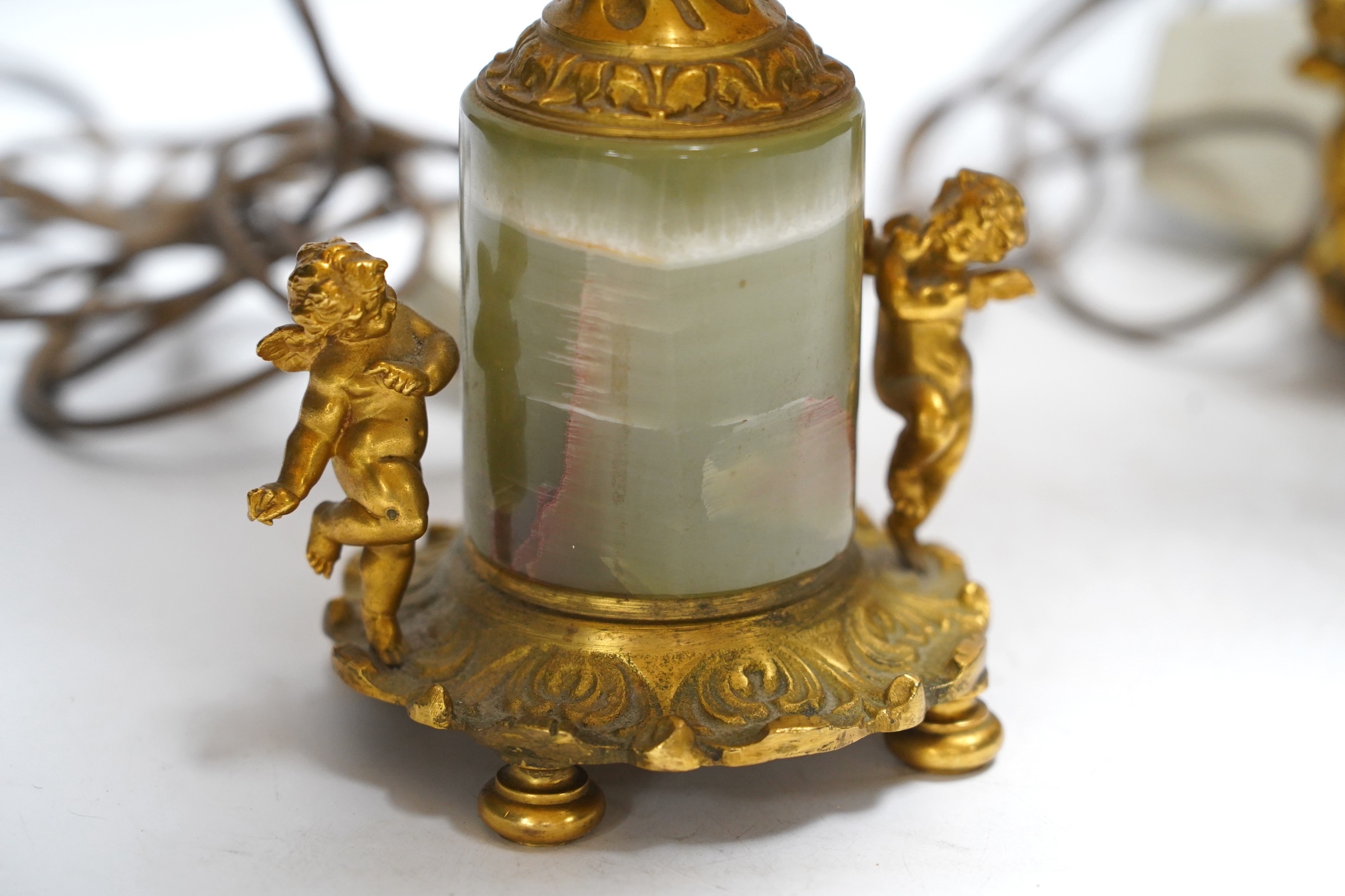 A pair of green onyx and gilt metal mounted cherub table lamps, 40cm high including the shades